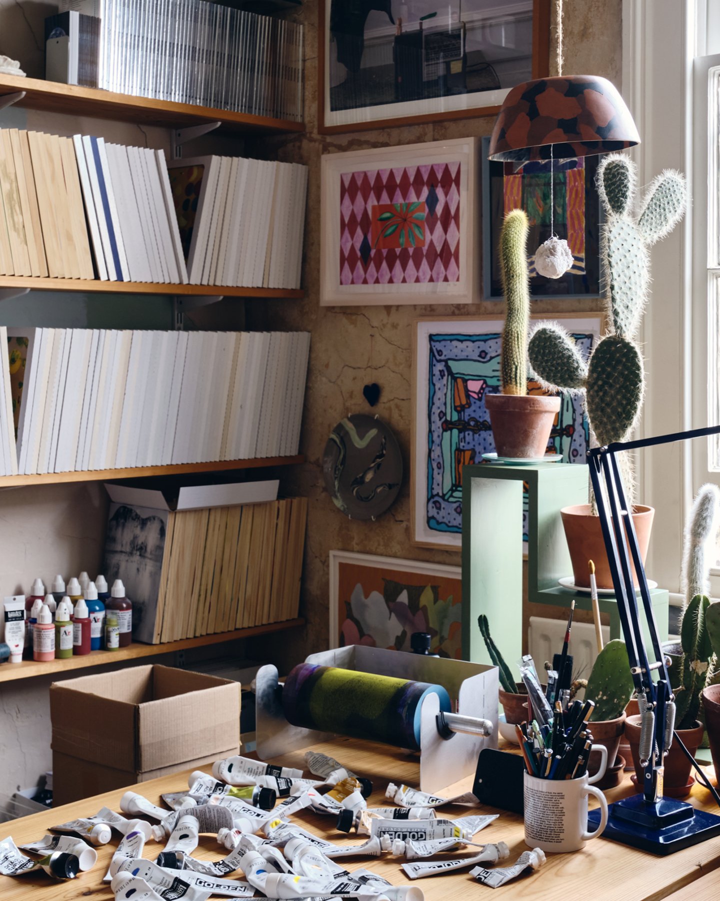 2. Artist Daniel Eatock’s London art studio work table covered with various paints and a rolling pin.