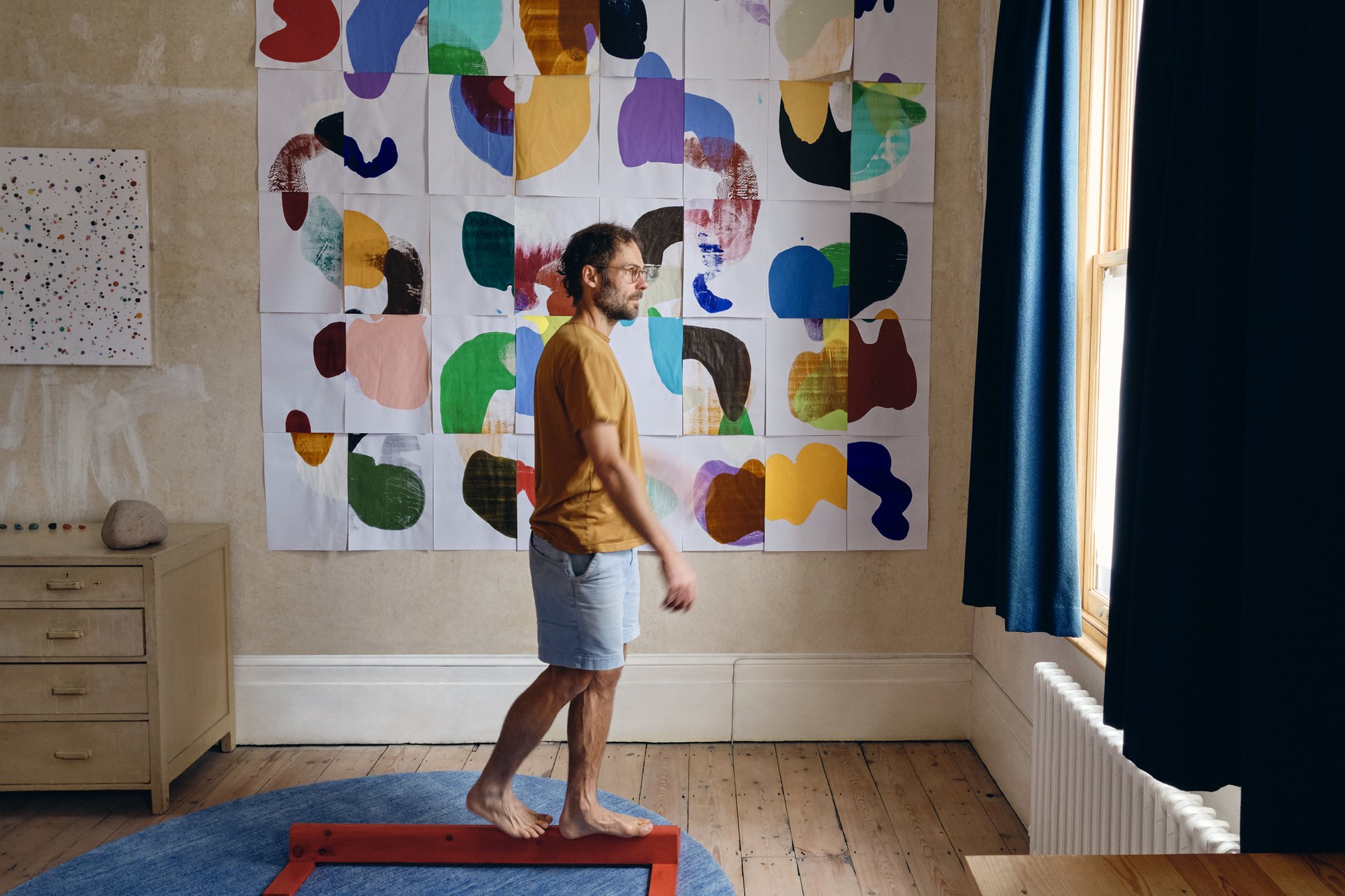 Artist Daniel Eatock in his London art studio with a wall of assembled roll forms from his rolling pin paintings.