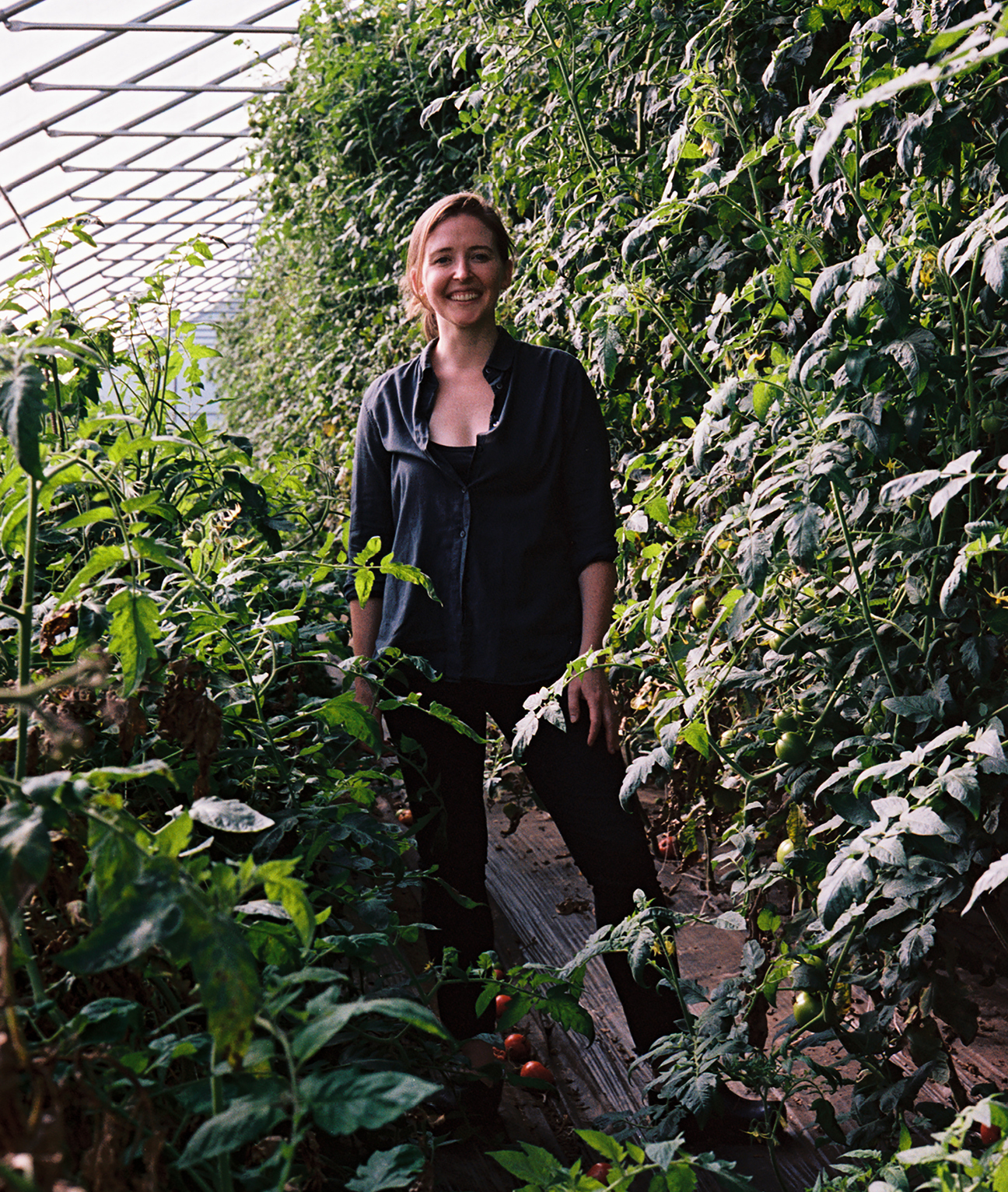 MASS Design Group's Caitlin Taylor surrounded by many large plantings at Four Root Farm in East Haddam, Connecticut.