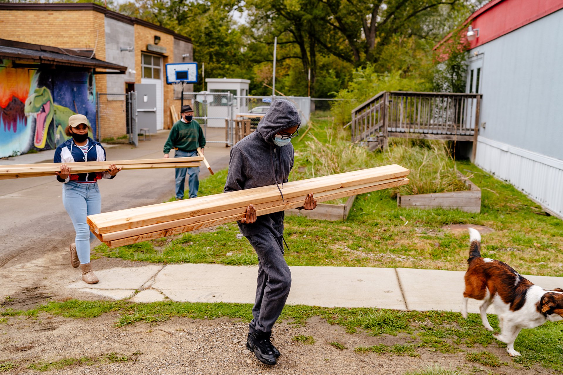 Several students at the Brightmoor Maker Space carrying large pieces of lumber outside the workshop.