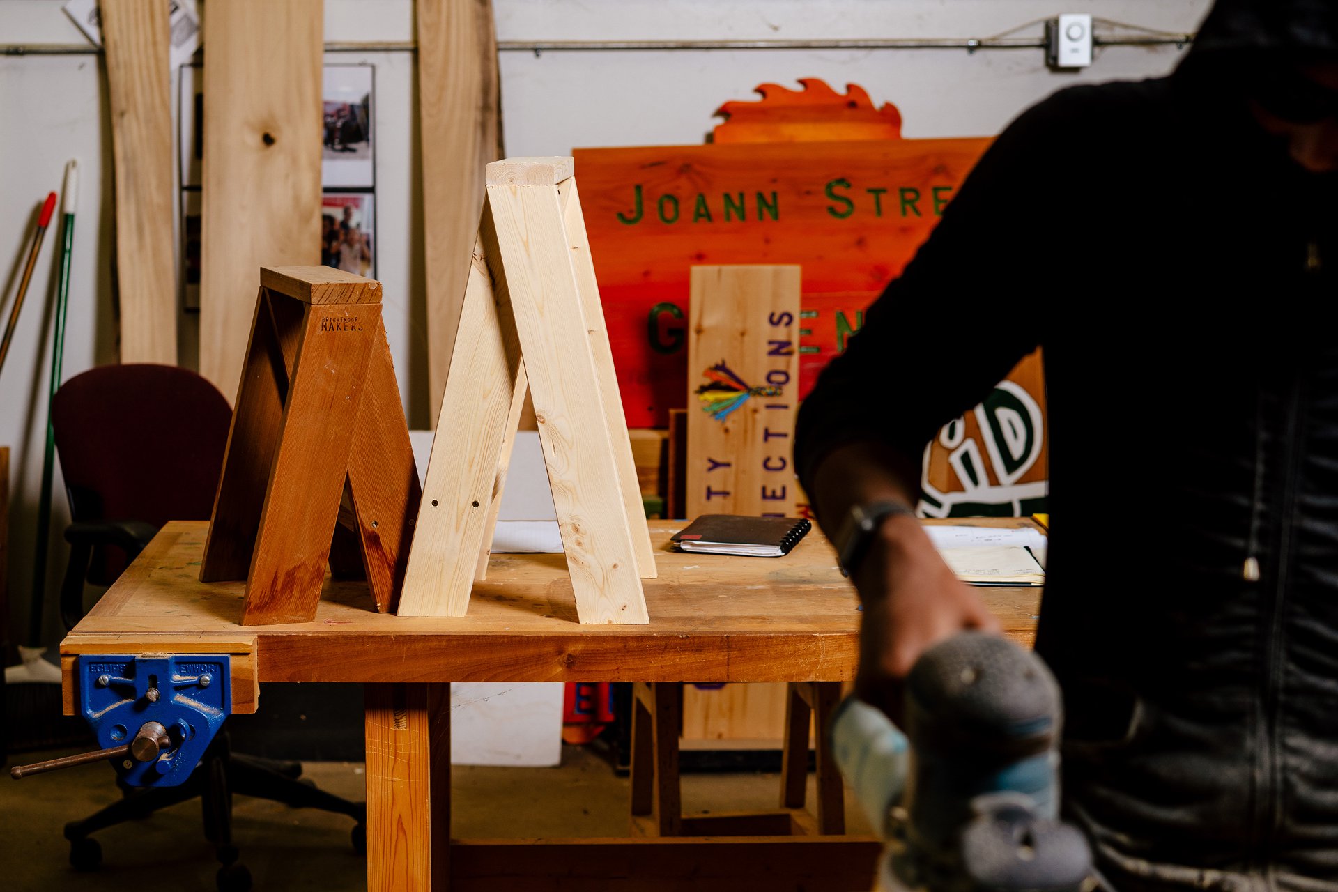 Handmade wooden stools on top of a wooden work table at the Brightmoor Maker Space, Kazam! Magazine.