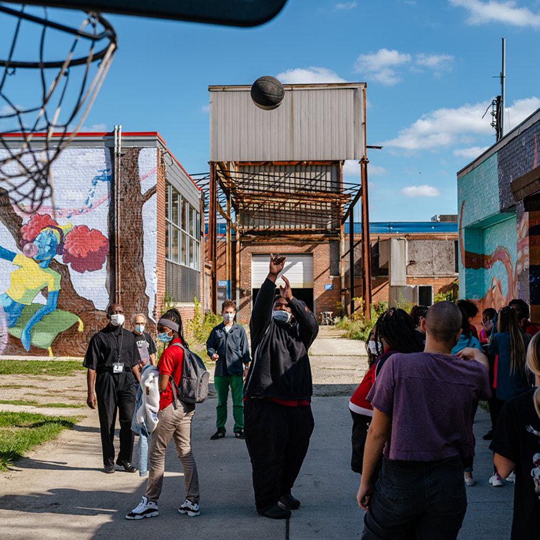 Several students play basketball outside the Brightmoor Maker Space, Kazam! Magazine.