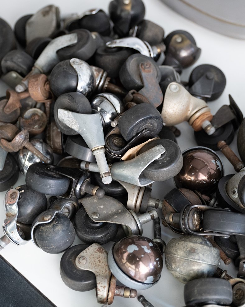 A pile of casters for Eames rolling chairs stacked on top of each other, Kazam! Magazine.