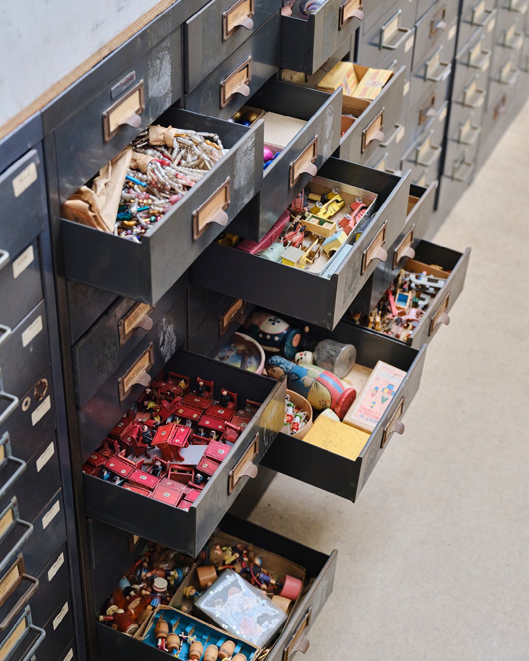 Cabinet with open drawers reveal various items that were a source of inspiration to Ray and Charles Eames, Kazam! Magazine.