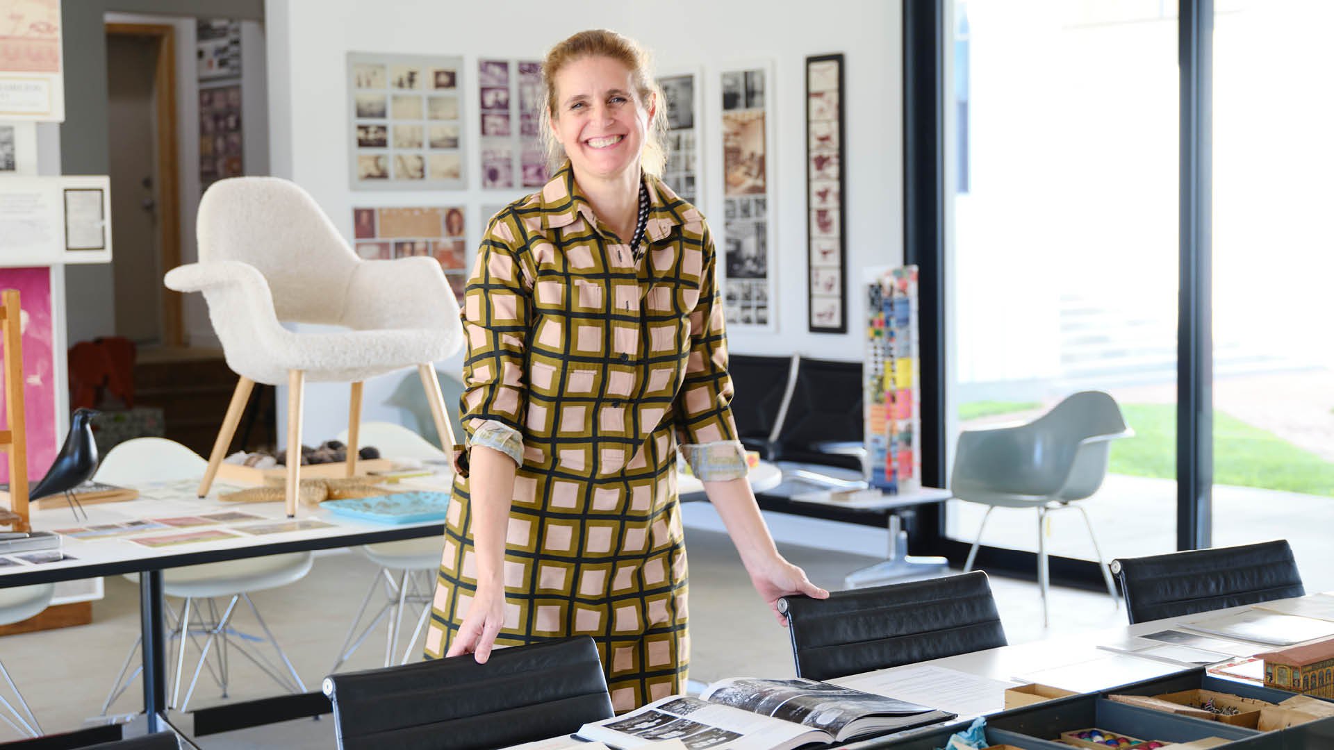 Llisa Demetrios, at the Eames institute, in a gallery, with designs and materials from the Eames collection, Kazam! Magazine.