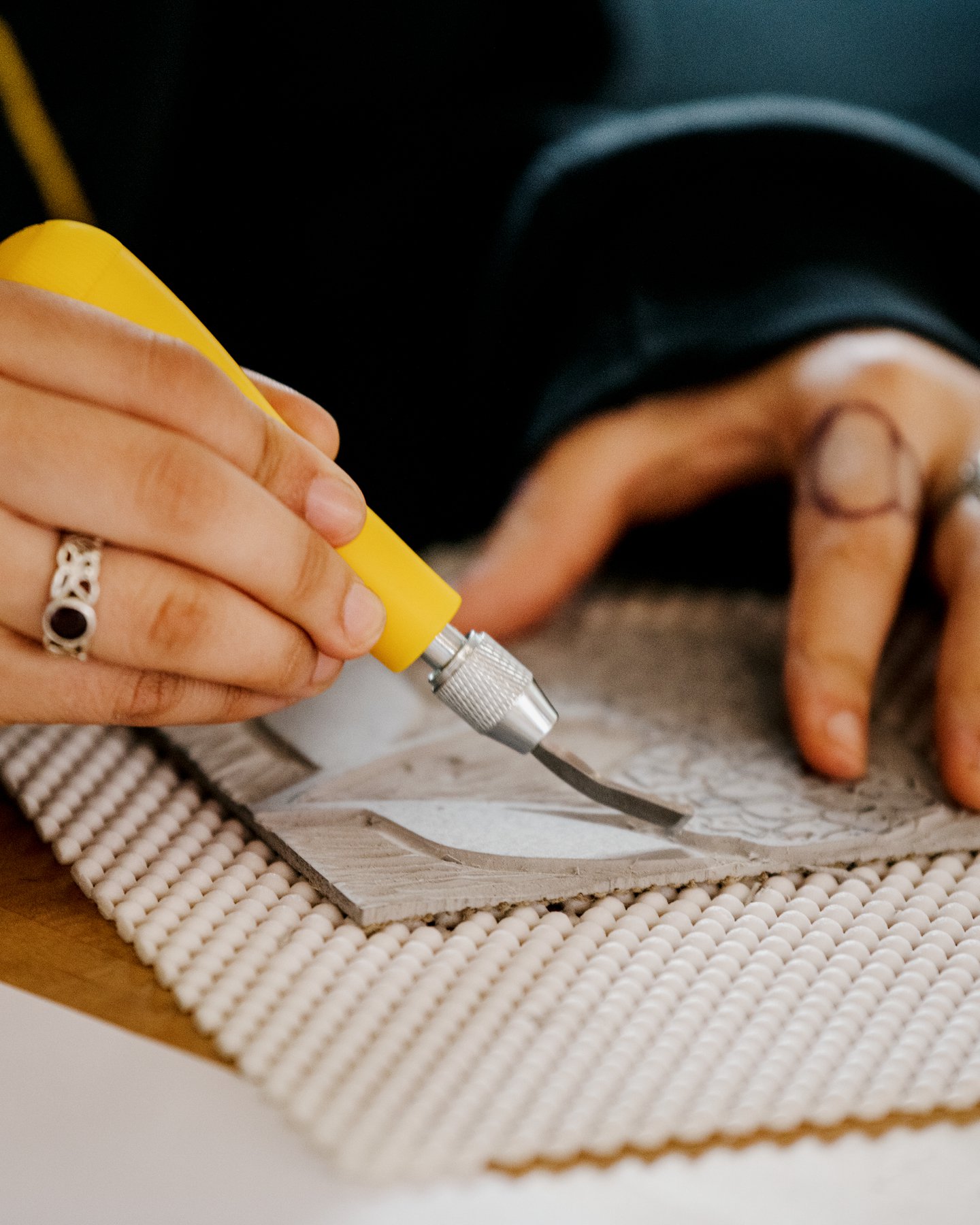 Girls Garage, a workshop and design/build program in Berkeley California, close up of hands carving lino for a block print.