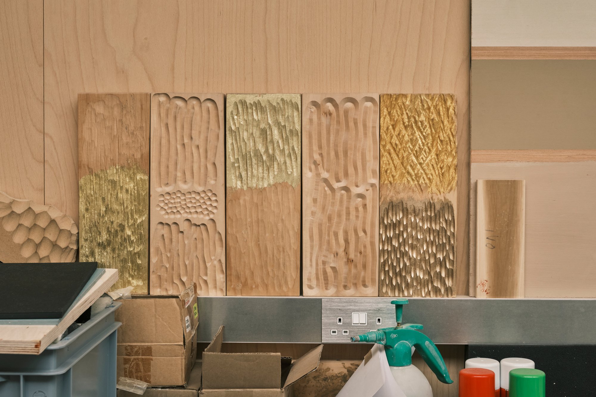 Carved lime wood experiments, some gilded in different colors of gold leaf, are samples for a work-in-progress in Max Lamb's workshop.