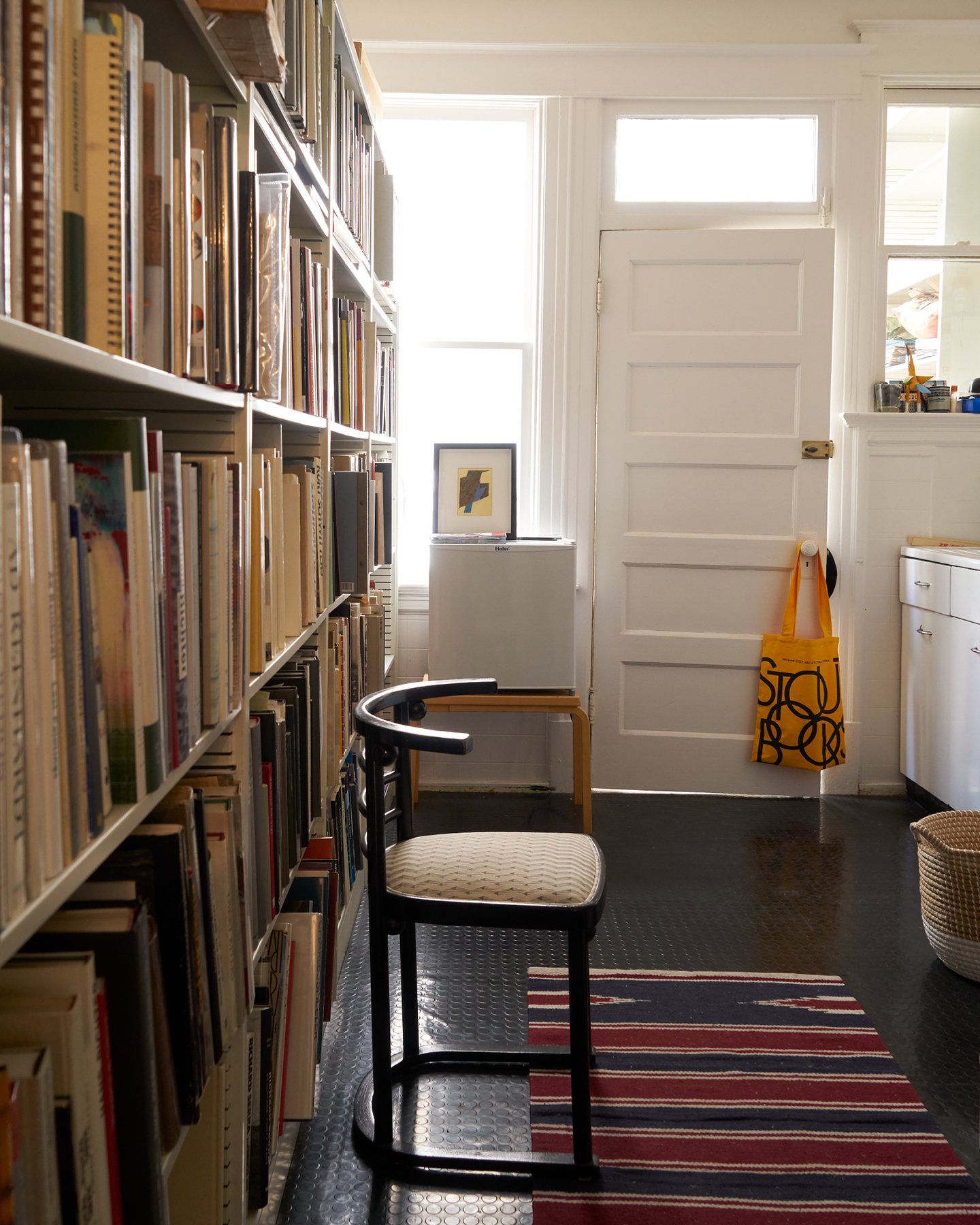 Interior view of bookshelves filling a wall in an entryway densely packed with architectural books.
